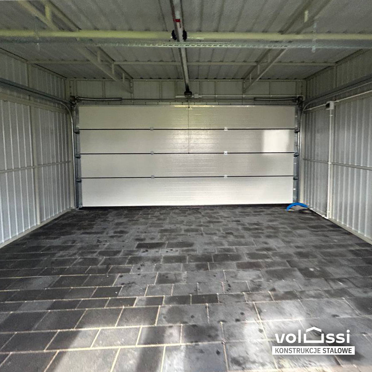 Wnętrze garażu z szeroką bramą — konstrukcja dachu i brama od środka